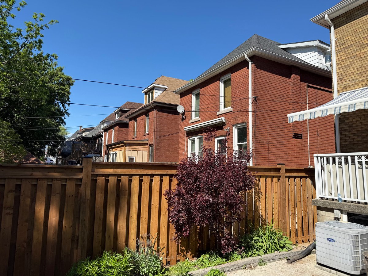 Row of red brick townhouses with wooden fences and clear blue sky